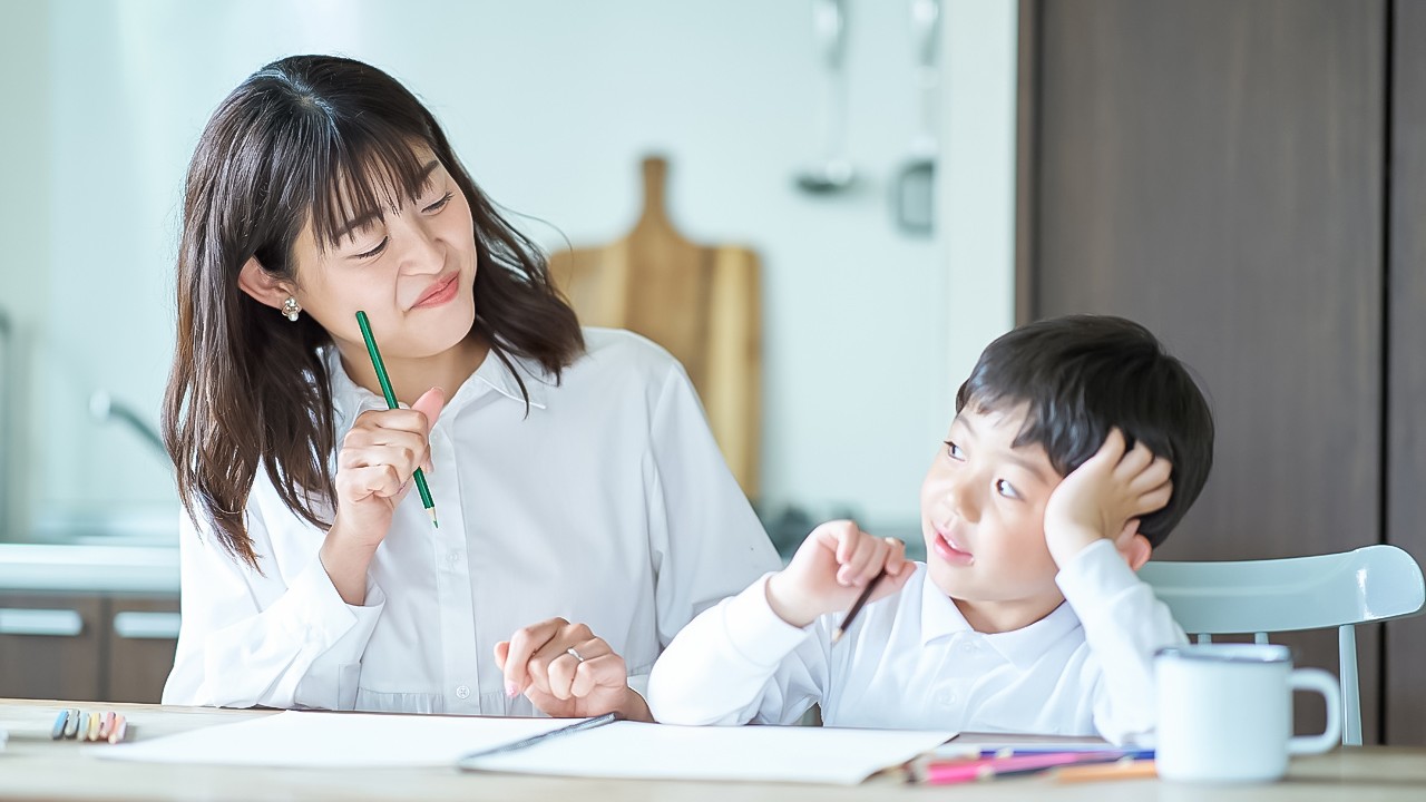 Mother and child studying with pencils and notebook
